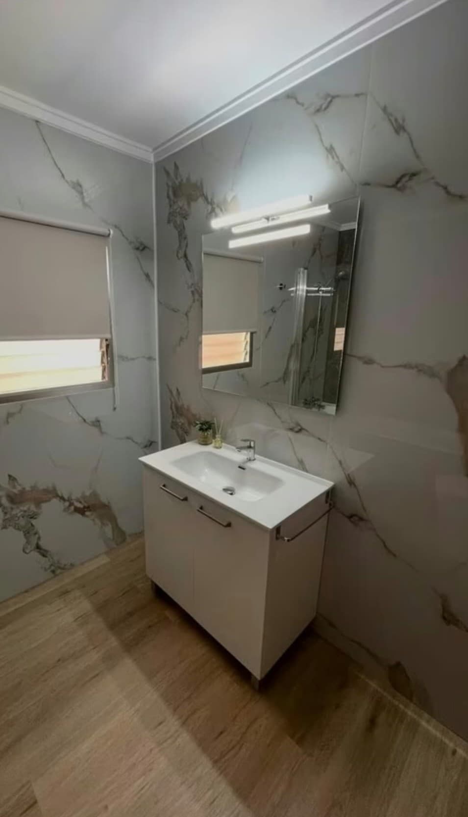 Baño reformado con mueble suspendido, plato de ducha y azulejos de gran formato